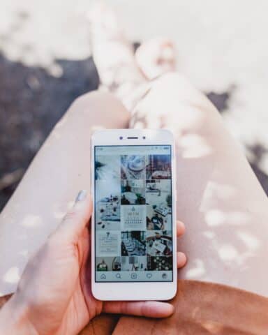 Eine Frau hält ein Smartphone in der Hand. Der Entdecken Feed von Instagram ist auf dem Smartphone geöffnet.